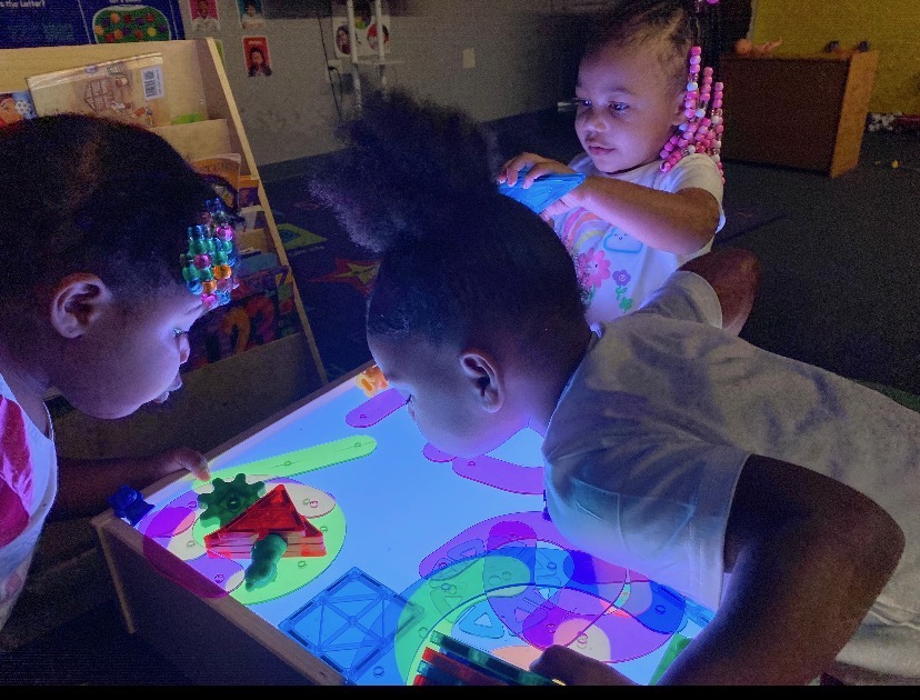 Children exploring a light table together during sensory play